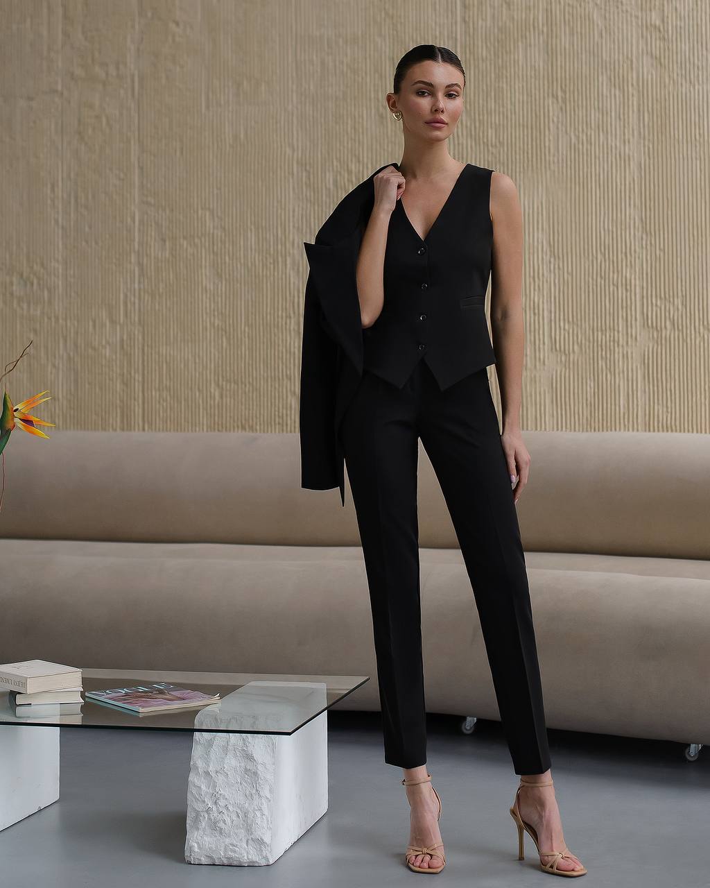 Woman in a black outfit standing in a modern living room.