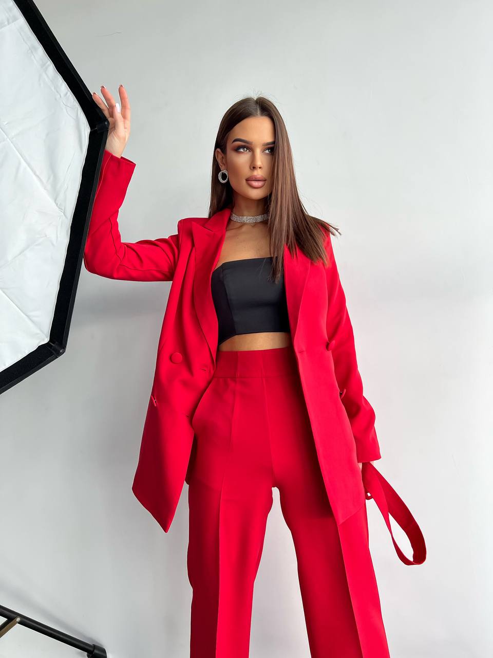 Woman wearing a red suit and black top in a studio setting