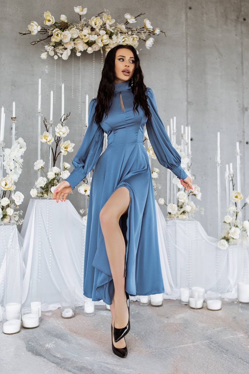 Woman in a blue dress standing in a decorated room with flowers and candles.