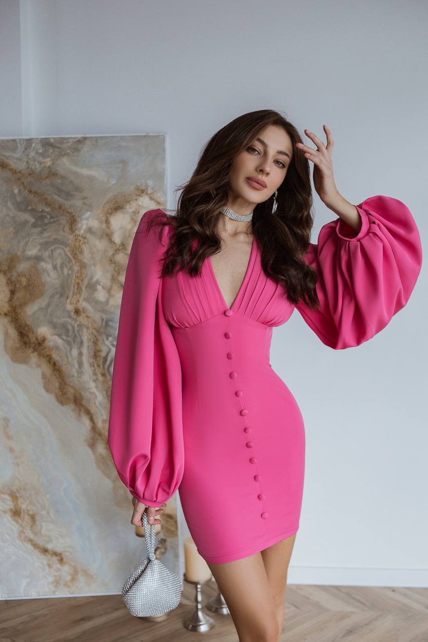 Woman wearing a bright pink dress with balloon sleeves in an indoor setting.