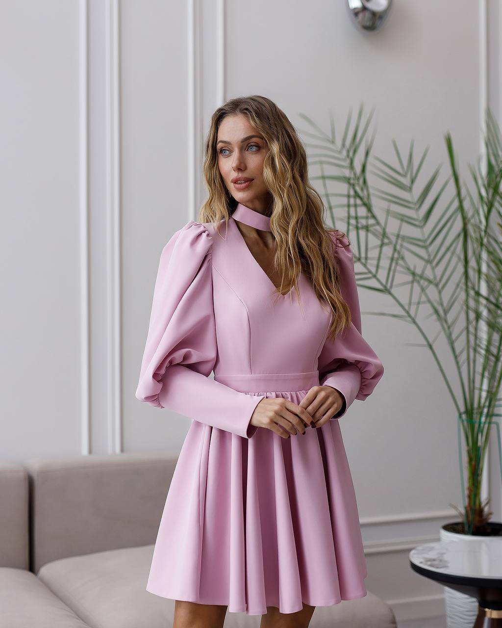 Woman wearing a pink dress with puffed sleeves in an indoor setting.