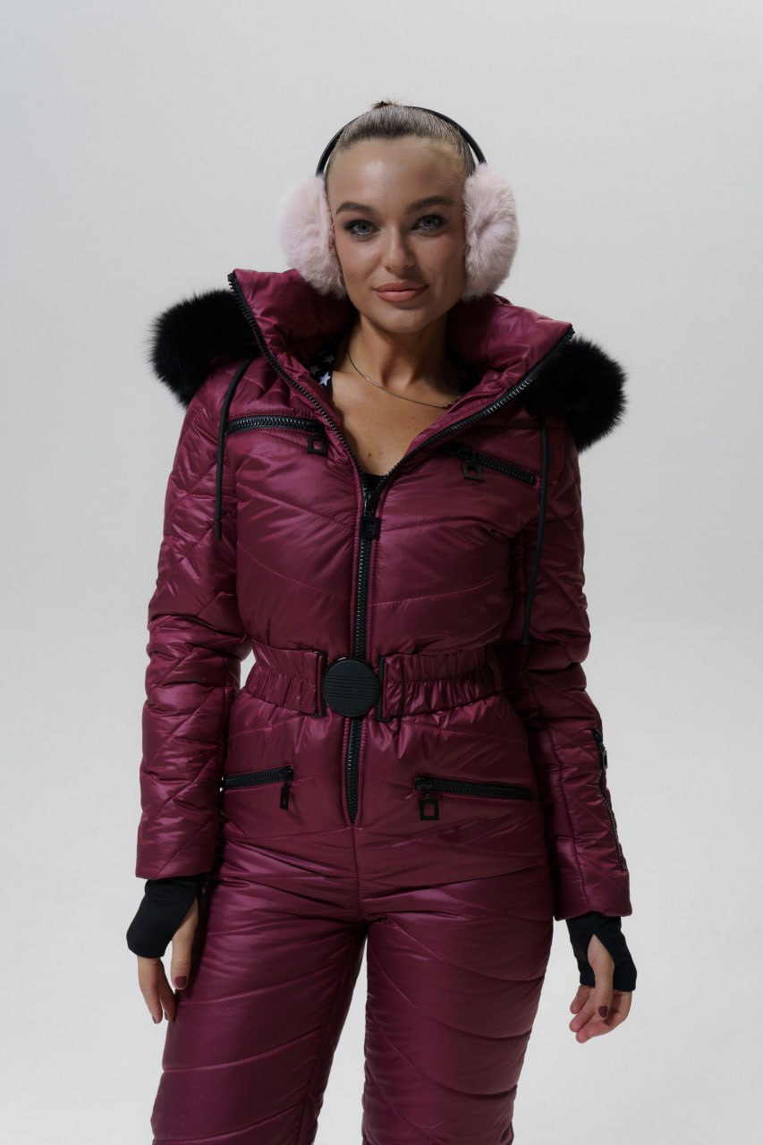 Person wearing a maroon snowsuit with black fur trim on a white background