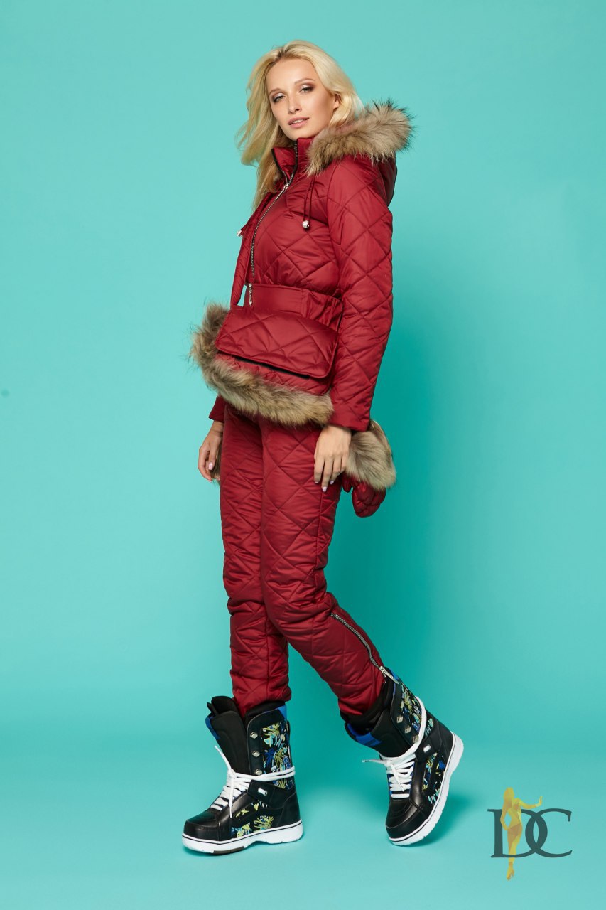 Person wearing a red winter outfit with fur trim on a teal background