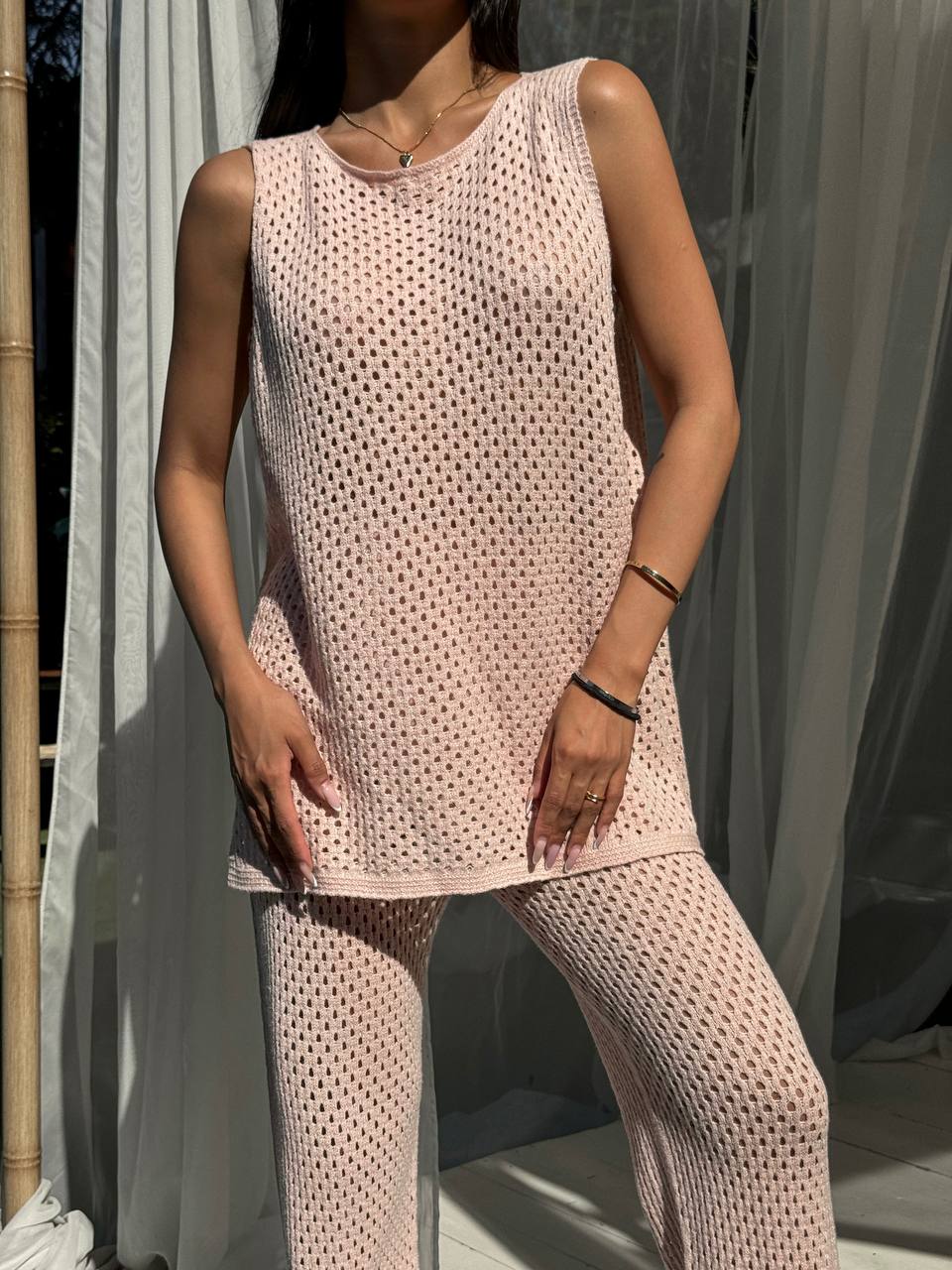 Person wearing a matching pink sleeveless top and pants set against a neutral background.
