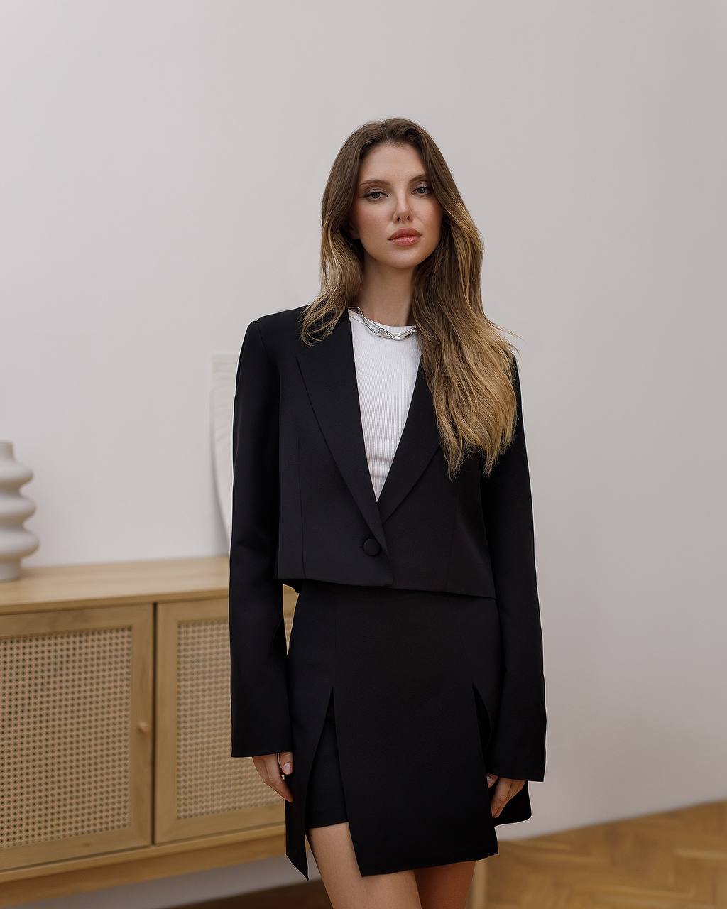 Woman wearing a black suit with a white shirt in an indoor setting