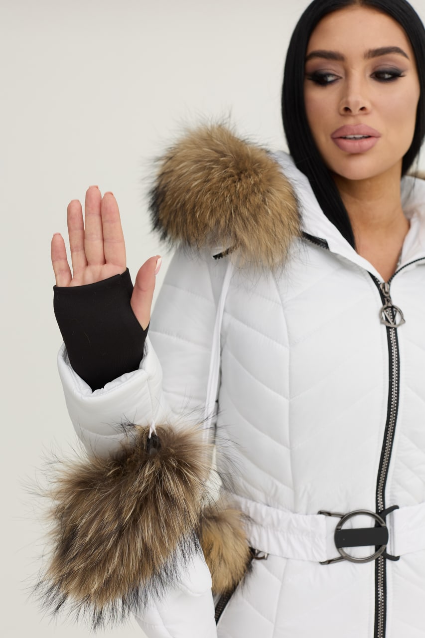 Woman wearing a white puffer jacket with fur-lined hood and cuffs on a plain background