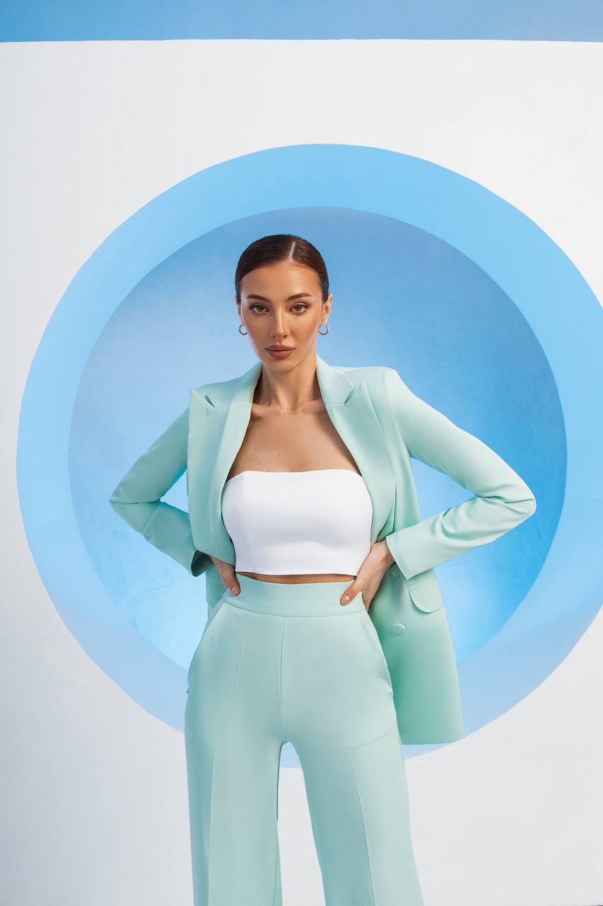 Woman in a light blue outfit standing against a blue circular background