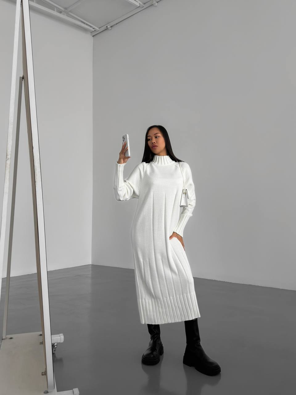 Woman in a white dress standing in a minimalistic room.
