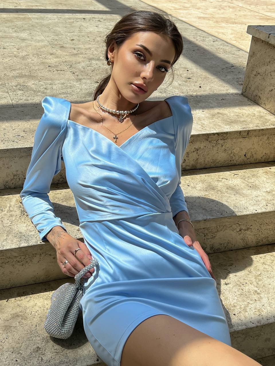 Woman in a light blue dress sitting on stone steps.