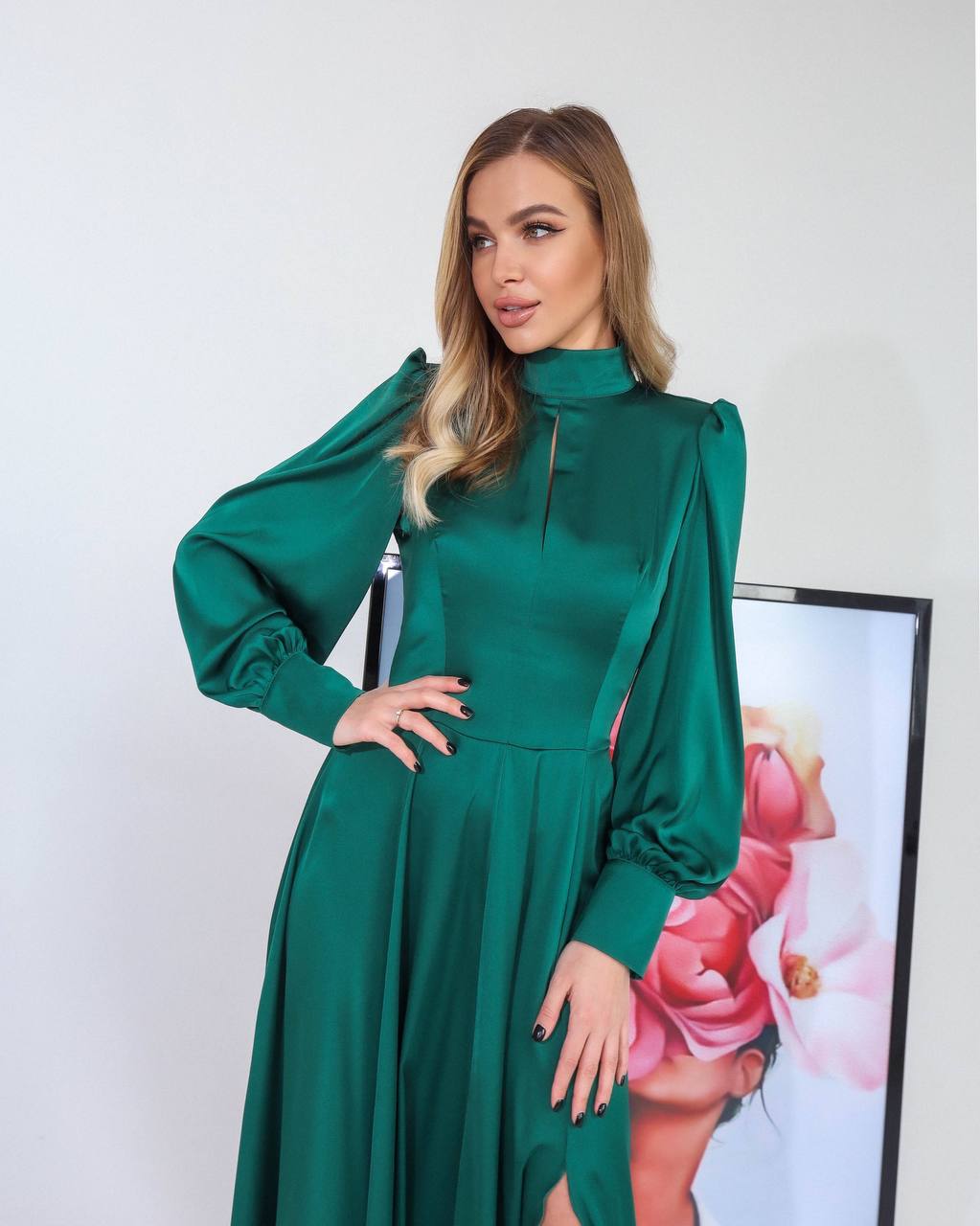 Woman wearing a green dress with long sleeves against a white background