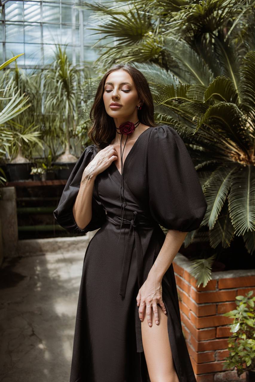 Woman in a black dress standing among plants in a greenhouse
