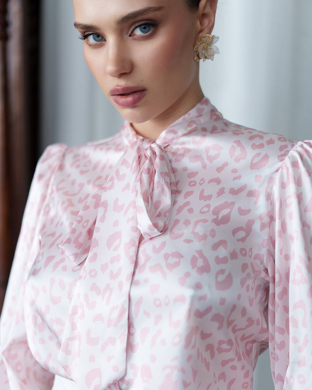 Woman wearing a pink leopard print blouse with a blurred background