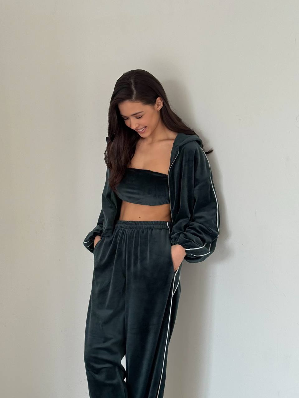 Woman wearing a dark green tracksuit against a plain background