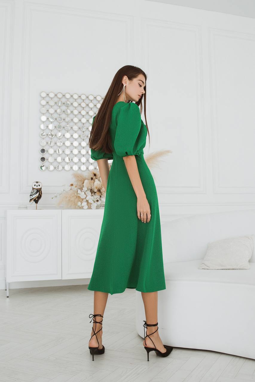 Woman in a green dress standing in a modern living room.