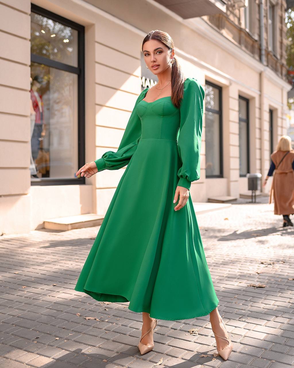 Woman in a green dress walking on a city street.