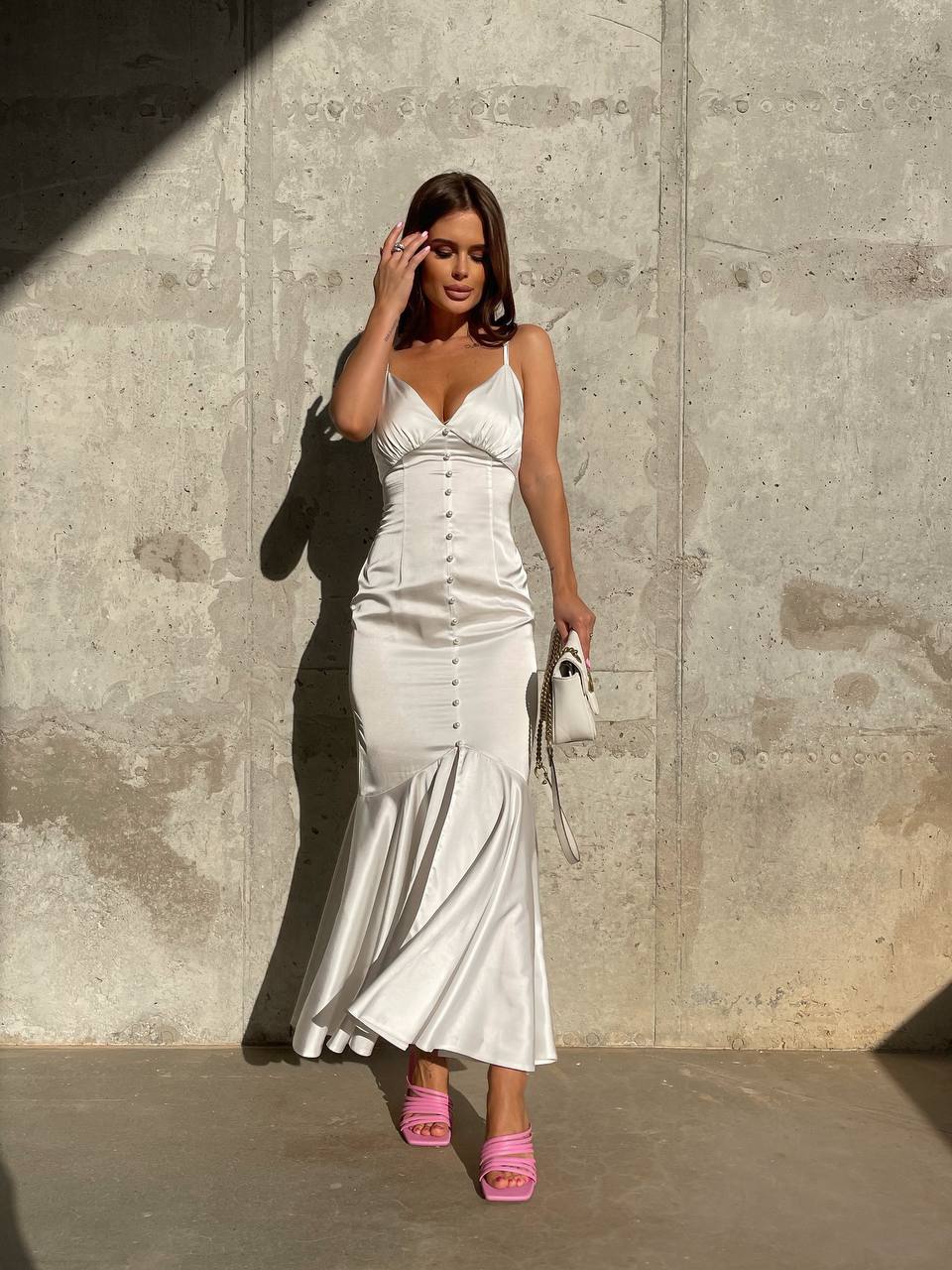 Woman in a white dress standing against a concrete wall