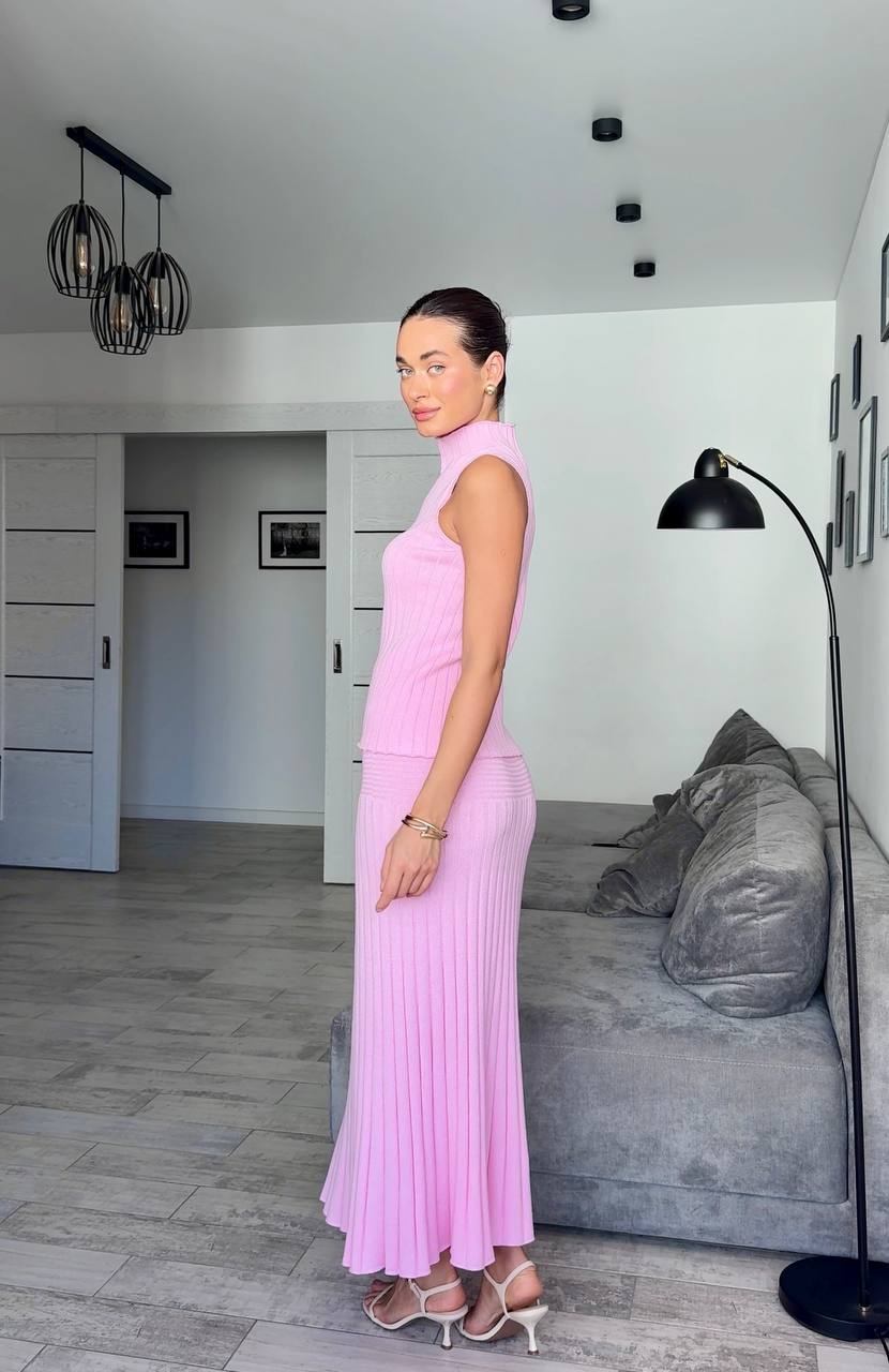 Woman in a pink dress standing in a modern living room.
