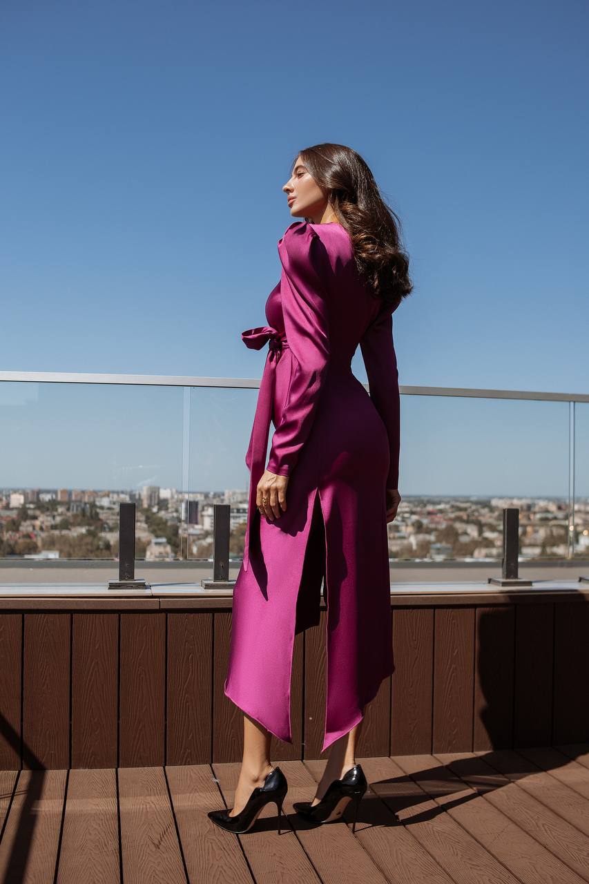 Woman in a magenta dress standing on a rooftop with a cityscape in the background