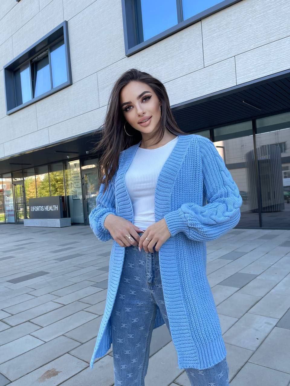 Woman wearing a blue cardigan standing outside a building