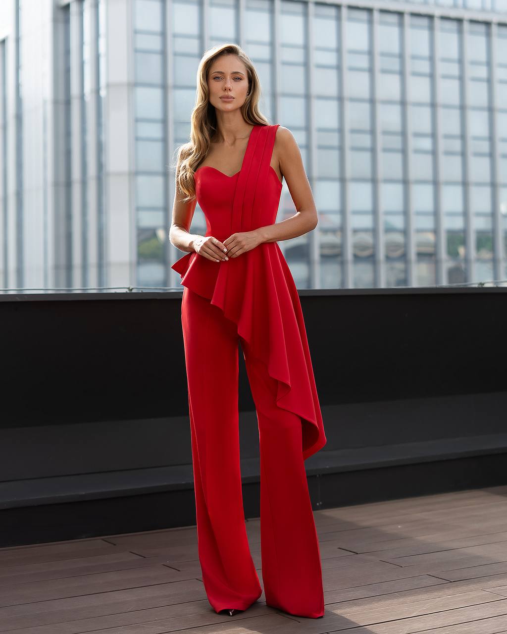 Woman wearing a red jumpsuit on a rooftop with cityscape background