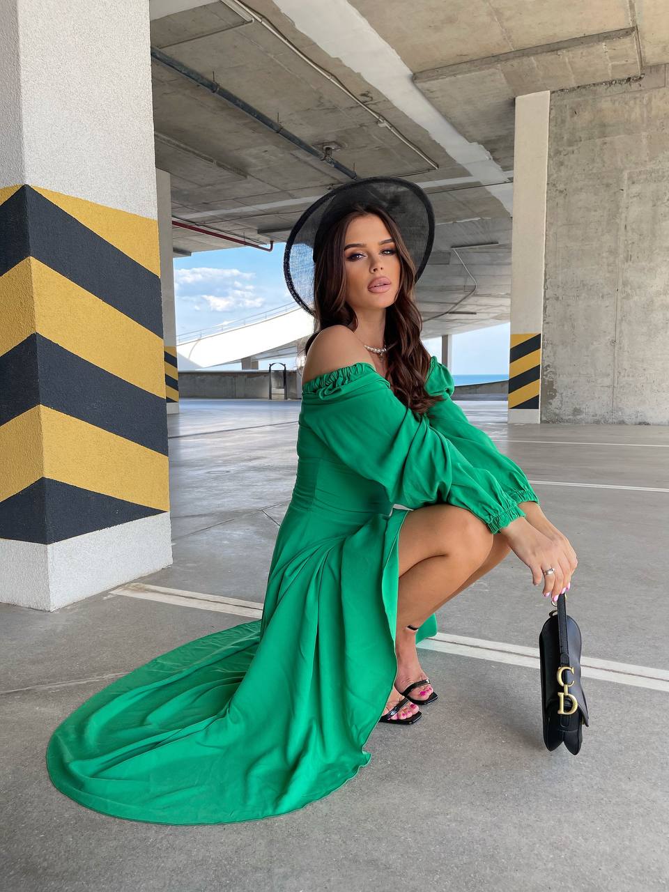 Woman in a green off-shoulder dress posing in an urban setting.