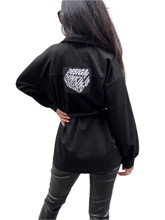 Person wearing a black jacket with text on the back against a white background