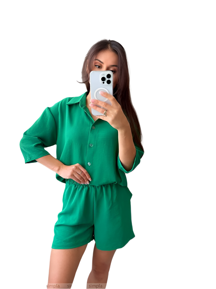 Woman taking a mirror selfie wearing a green outfit on a white background
