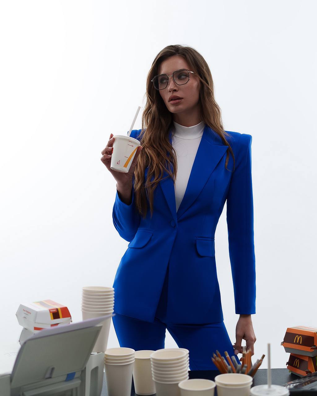 Woman in a blue suit holding a McDonald's cup with a white background