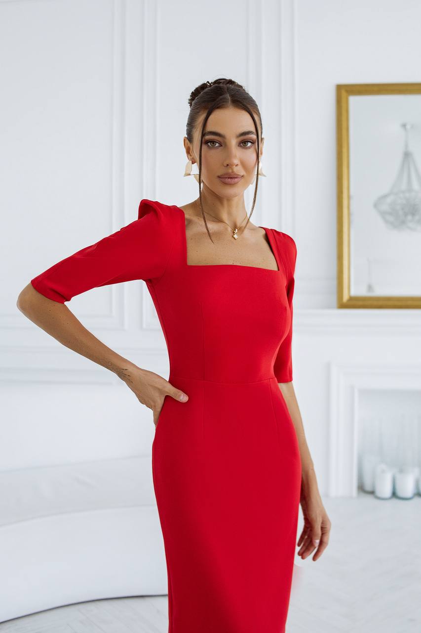 Woman wearing a red dress in a white room with a painting on the wall.
