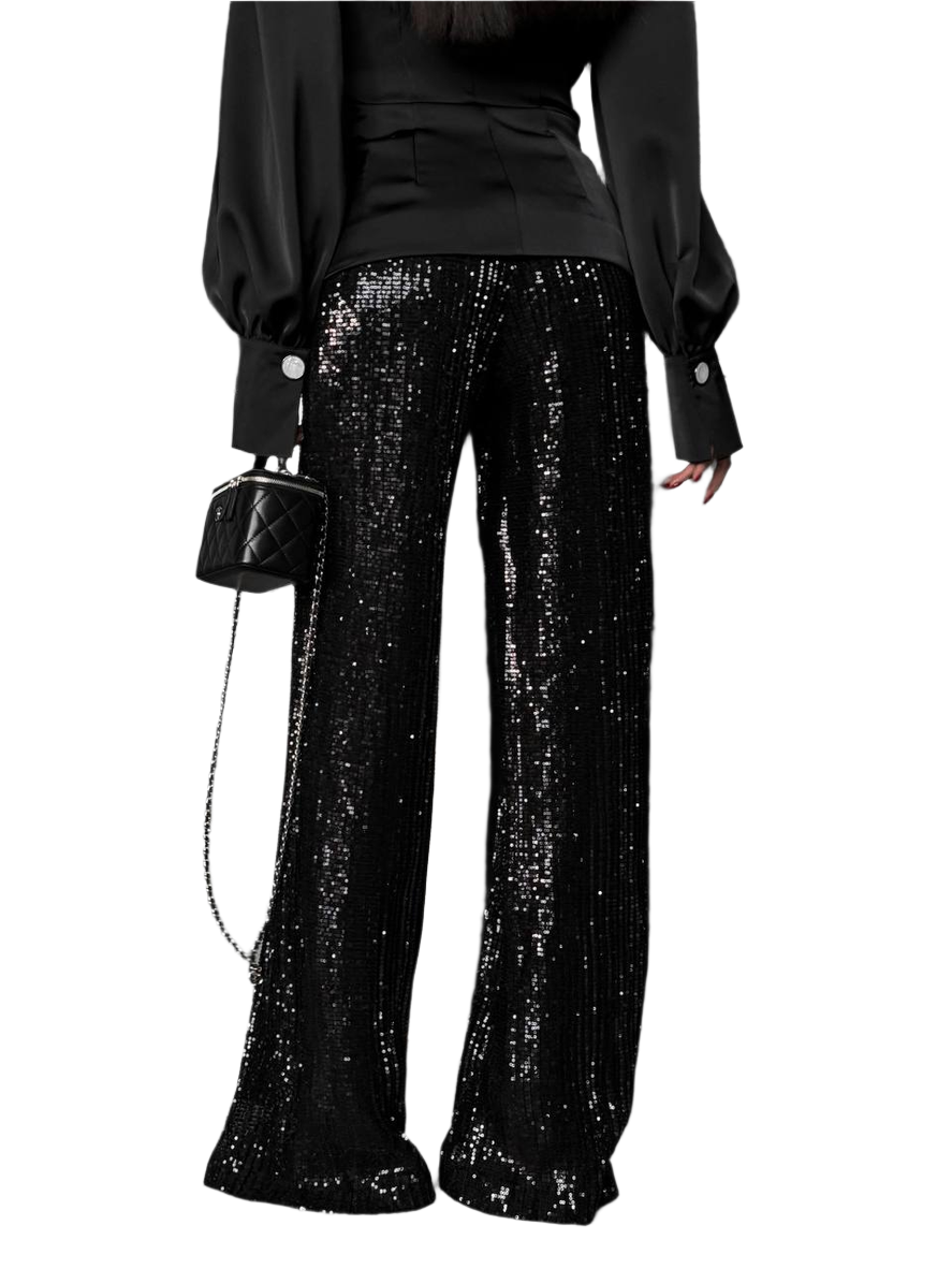 Person wearing black sequin pants with a black top and handbag on a white background