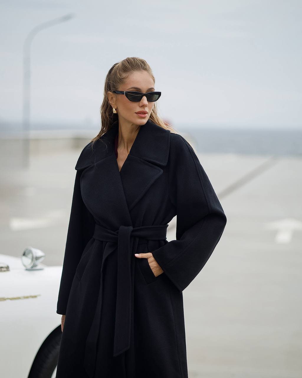 Woman wearing a black coat and sunglasses in an urban setting