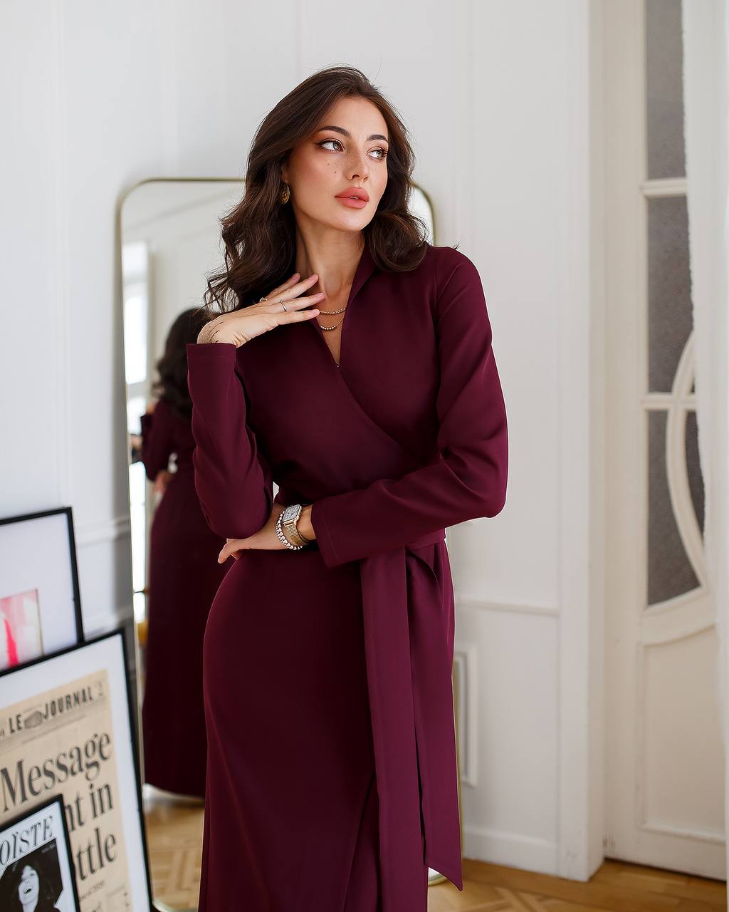 Woman wearing a burgundy dress standing in front of a mirror.