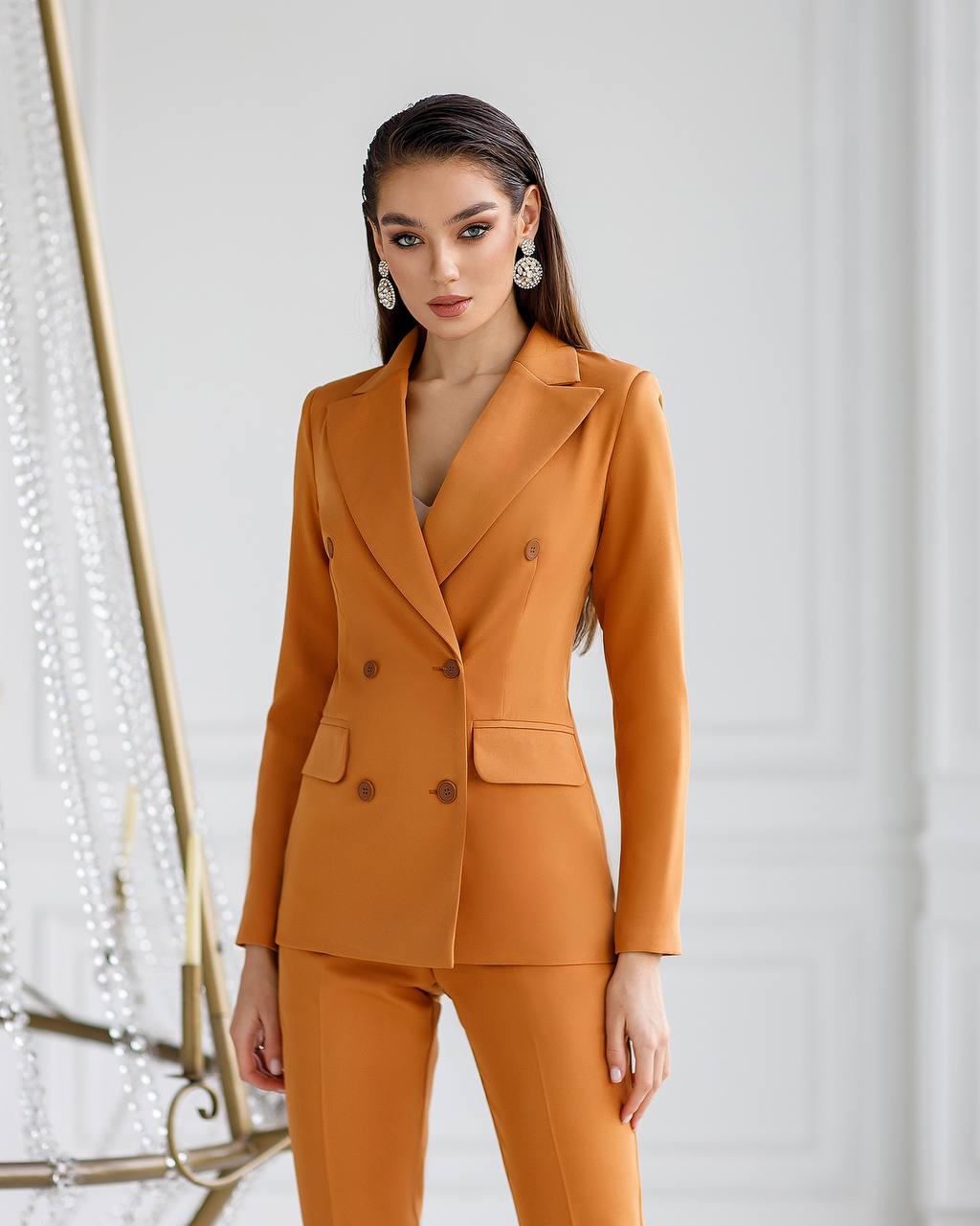 Woman wearing an orange suit against a white background
