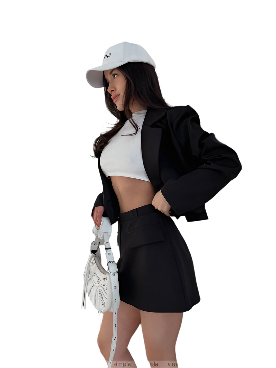 Woman in black blazer and skirt with white top, holding a white bag on a white background