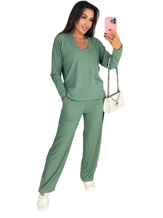 Woman wearing a green outfit taking a selfie on a white background
