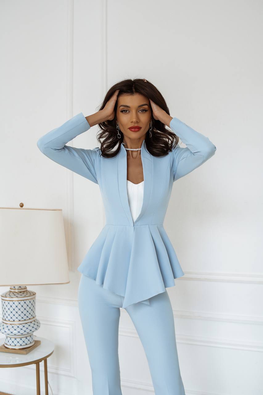 Woman wearing a light blue peplum suit against a white background