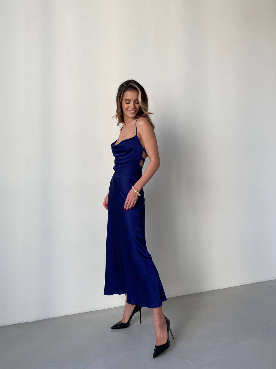 Woman wearing a blue satin dress against a plain background