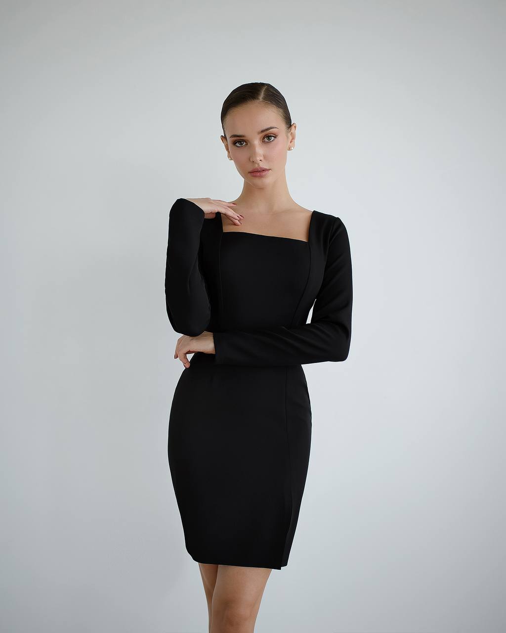 Woman wearing a black dress against a plain background