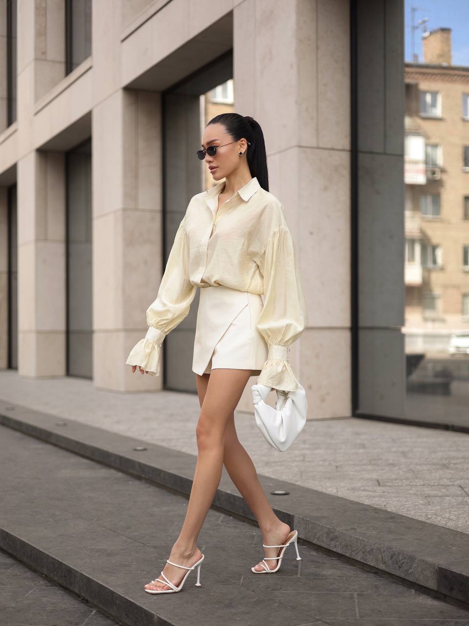 Woman in a white outfit walking on a city street.
