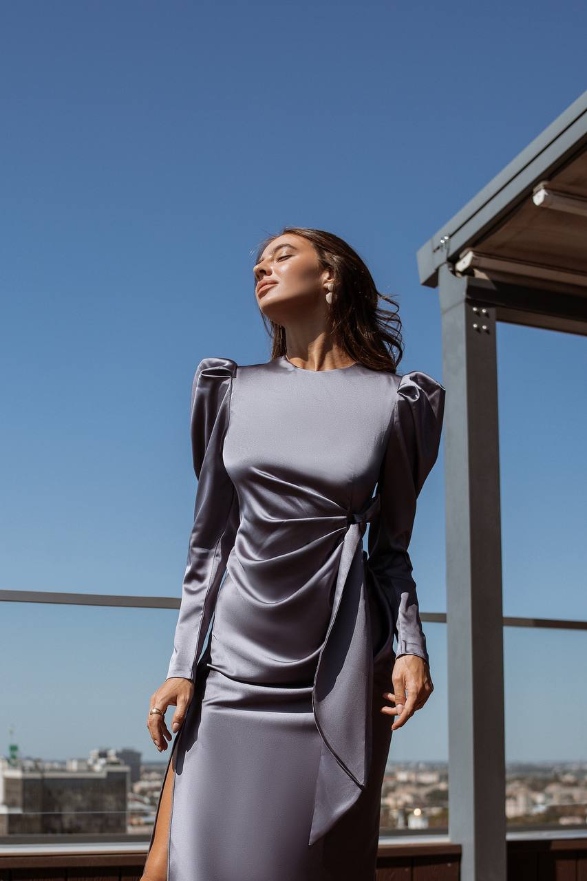 Woman in a gray dress standing on a rooftop with a clear blue sky