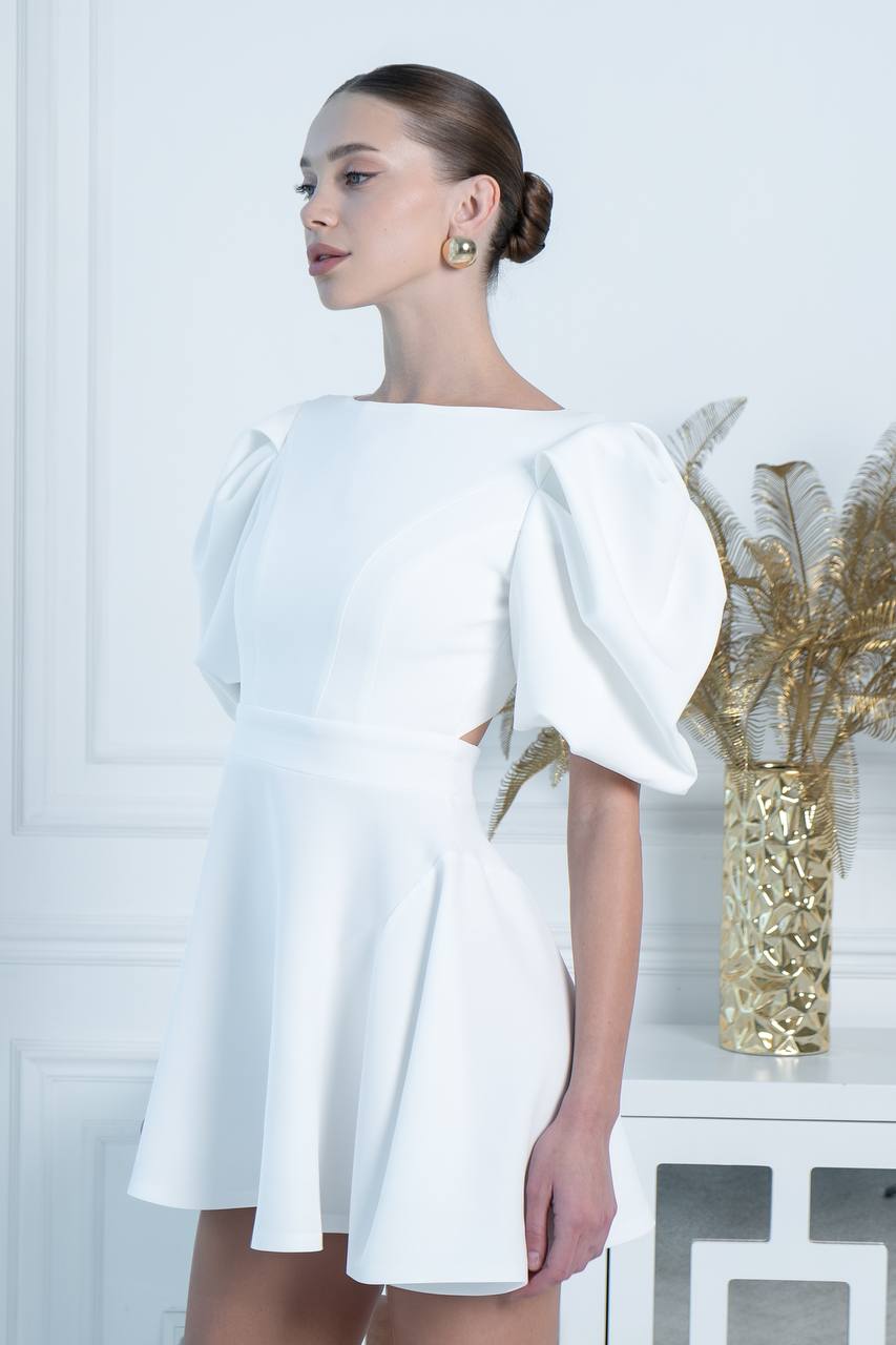 Woman wearing a white dress with puffed sleeves in an indoor setting.