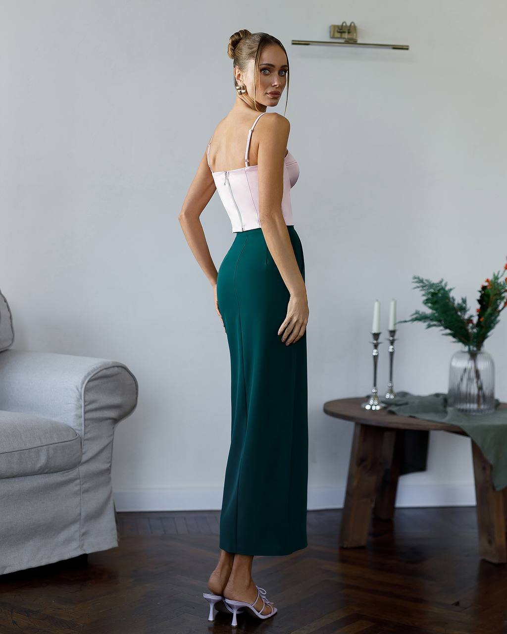 Woman in a green dress standing in a room with a couch and table in the background