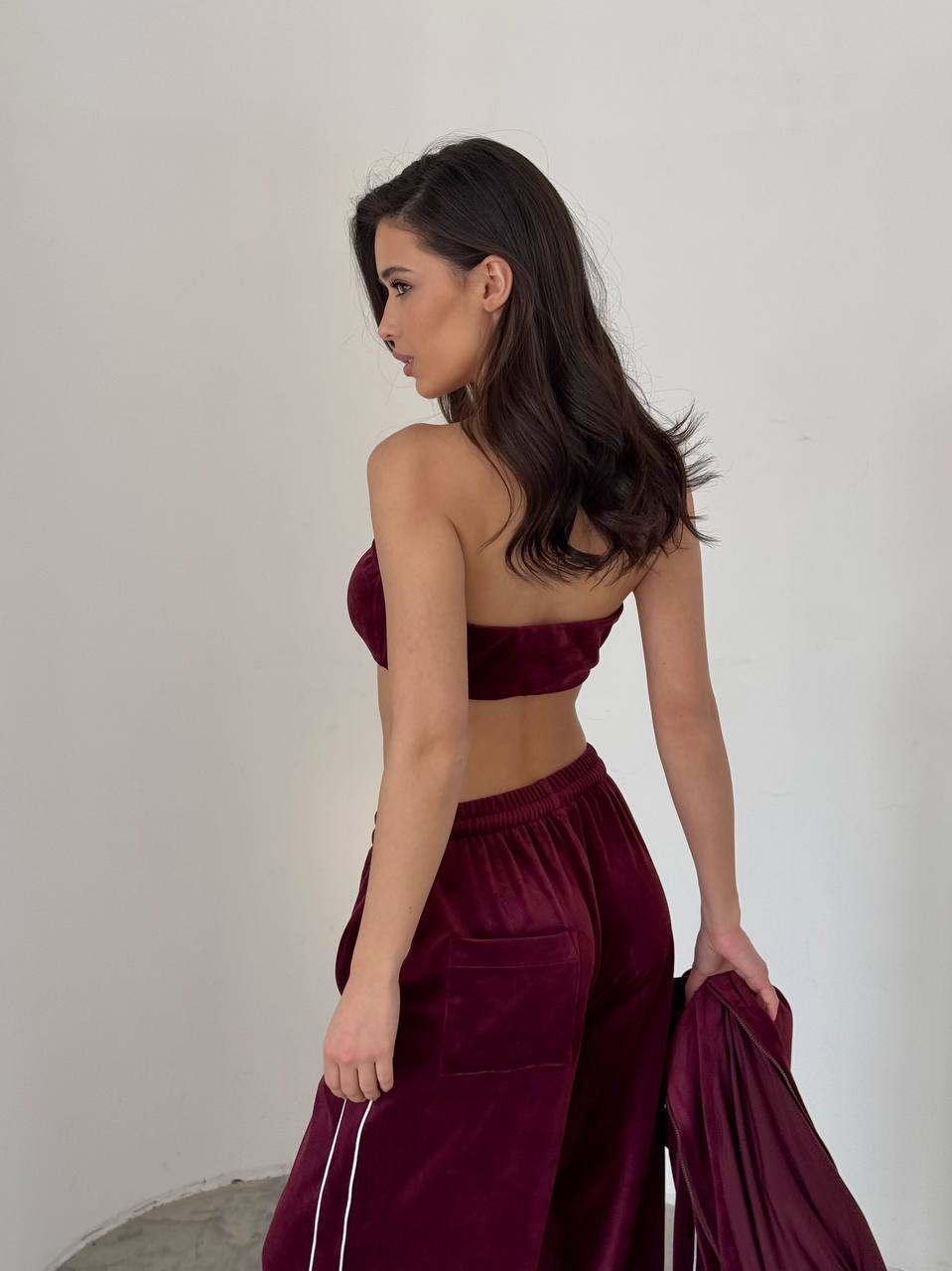 Woman wearing a burgundy velvet outfit against a plain background
