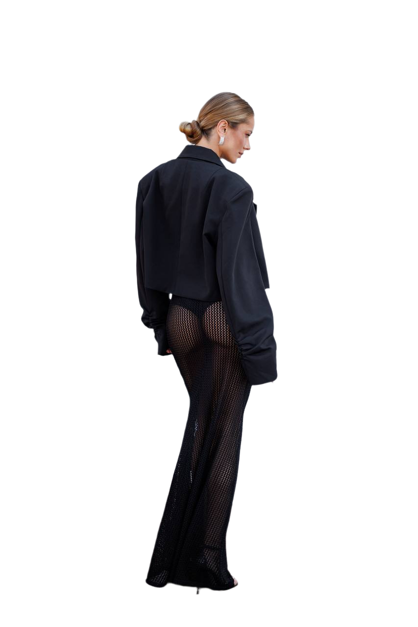 Person wearing a black outfit with sheer stockings on a white background
