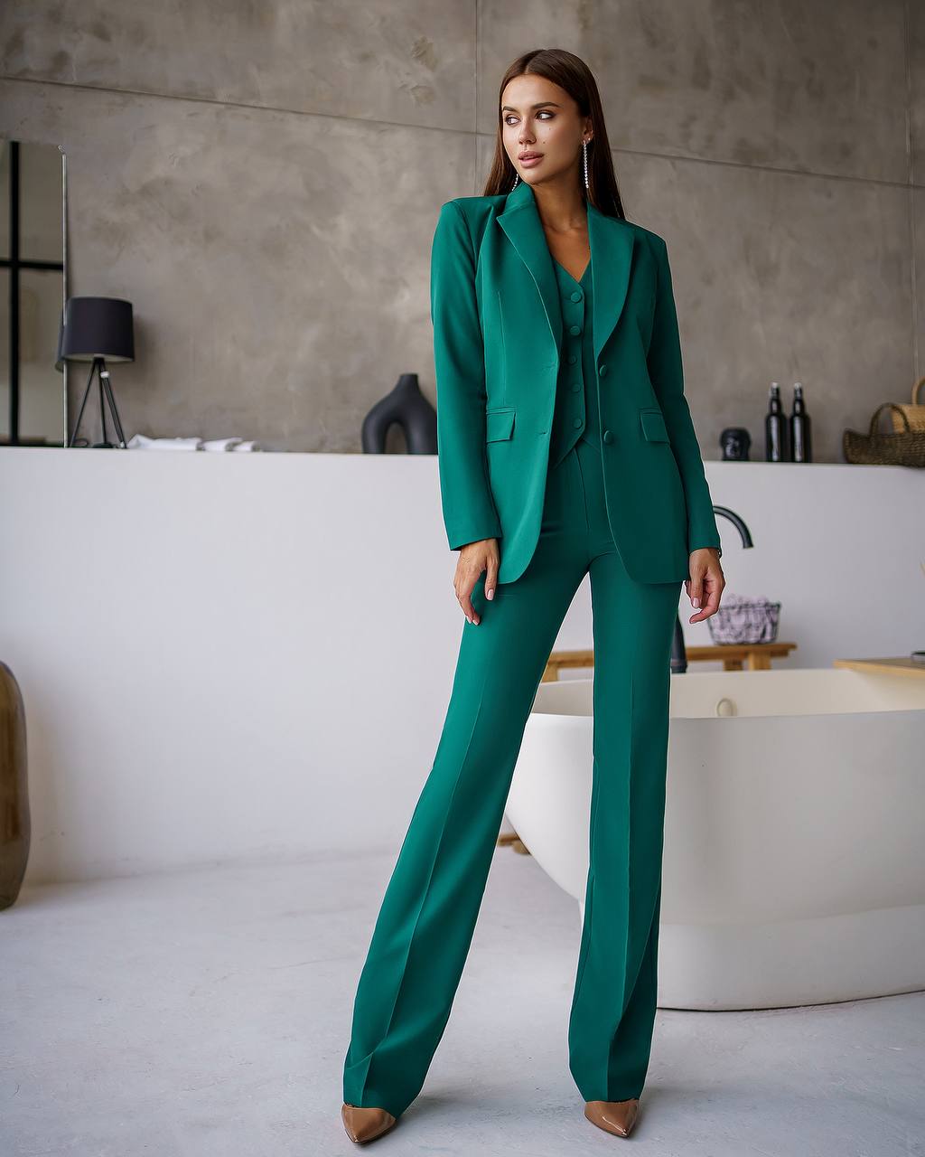 Woman in a green suit standing in a modern bathroom.