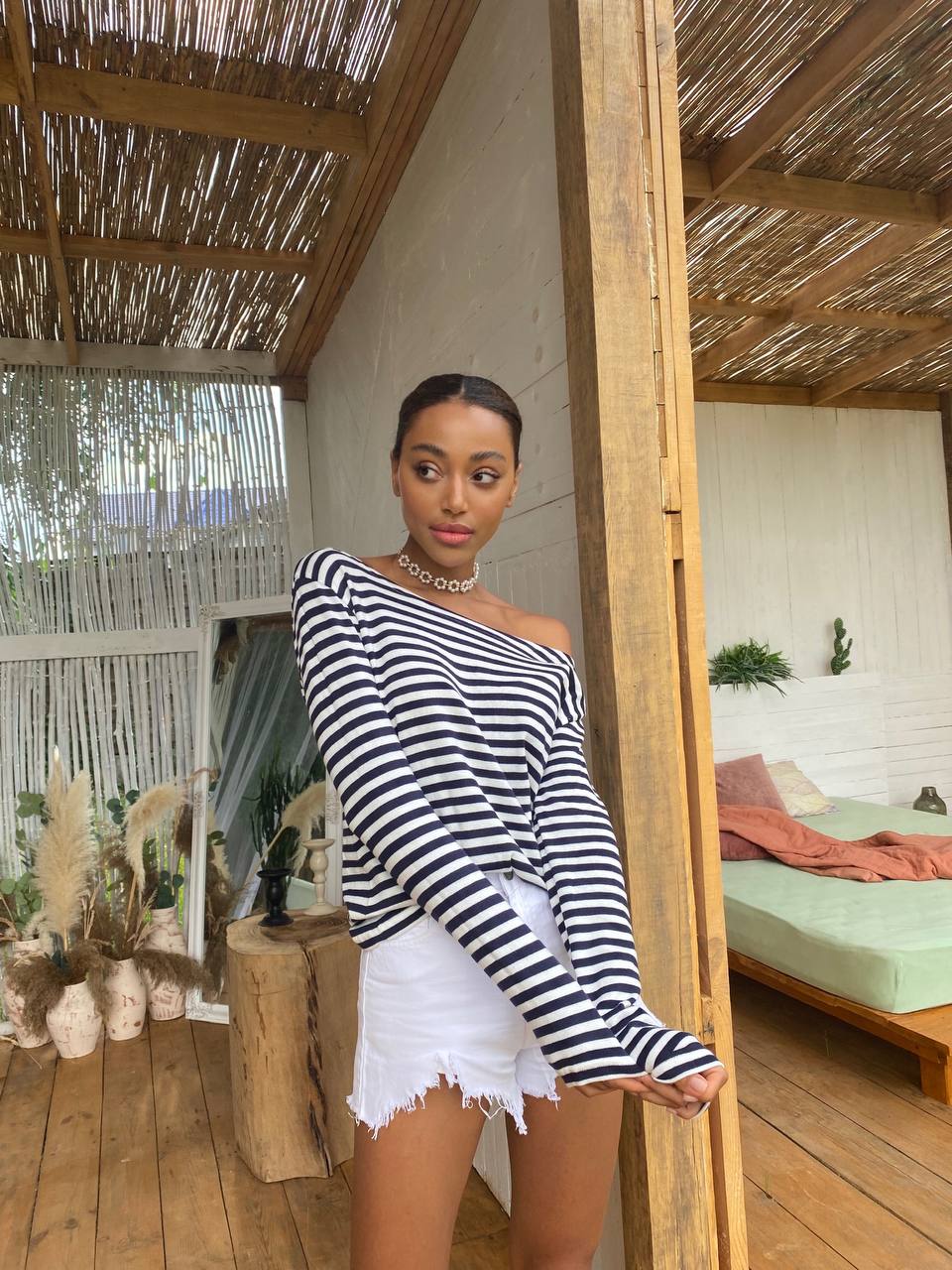 Woman in a striped top and white shorts standing in a wooden interior setting.