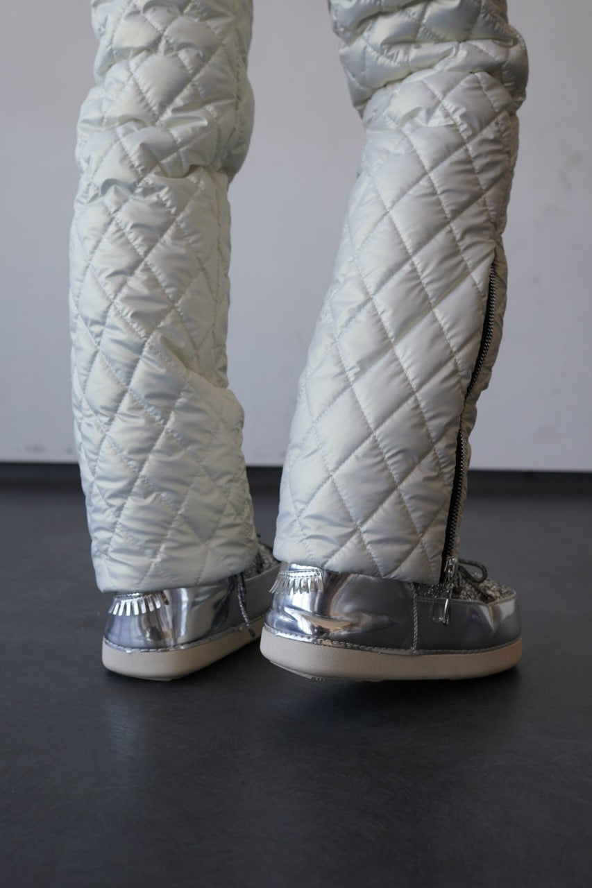 Quilted silver pants with reflective shoes on a dark floor.