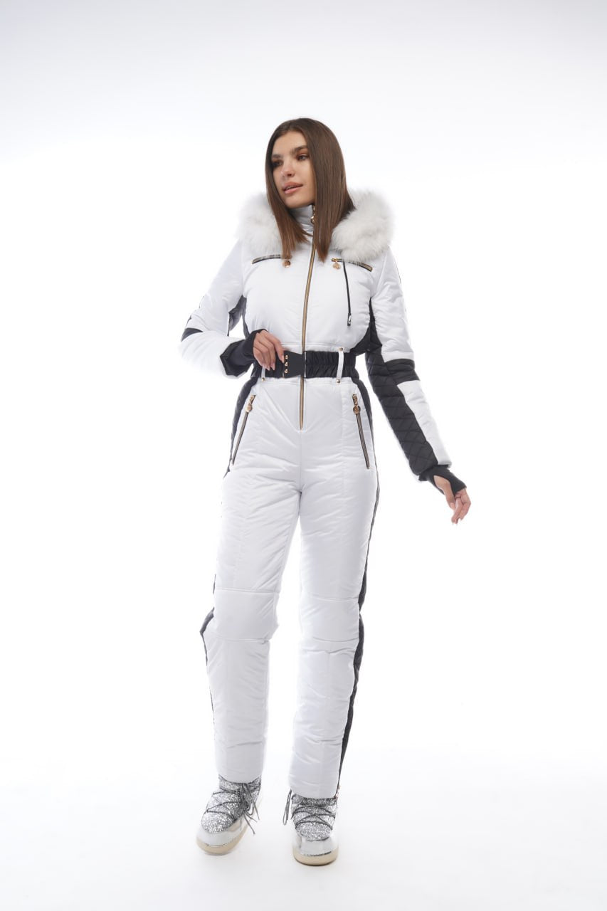 Woman wearing a white and black ski suit with fur trim on a white background