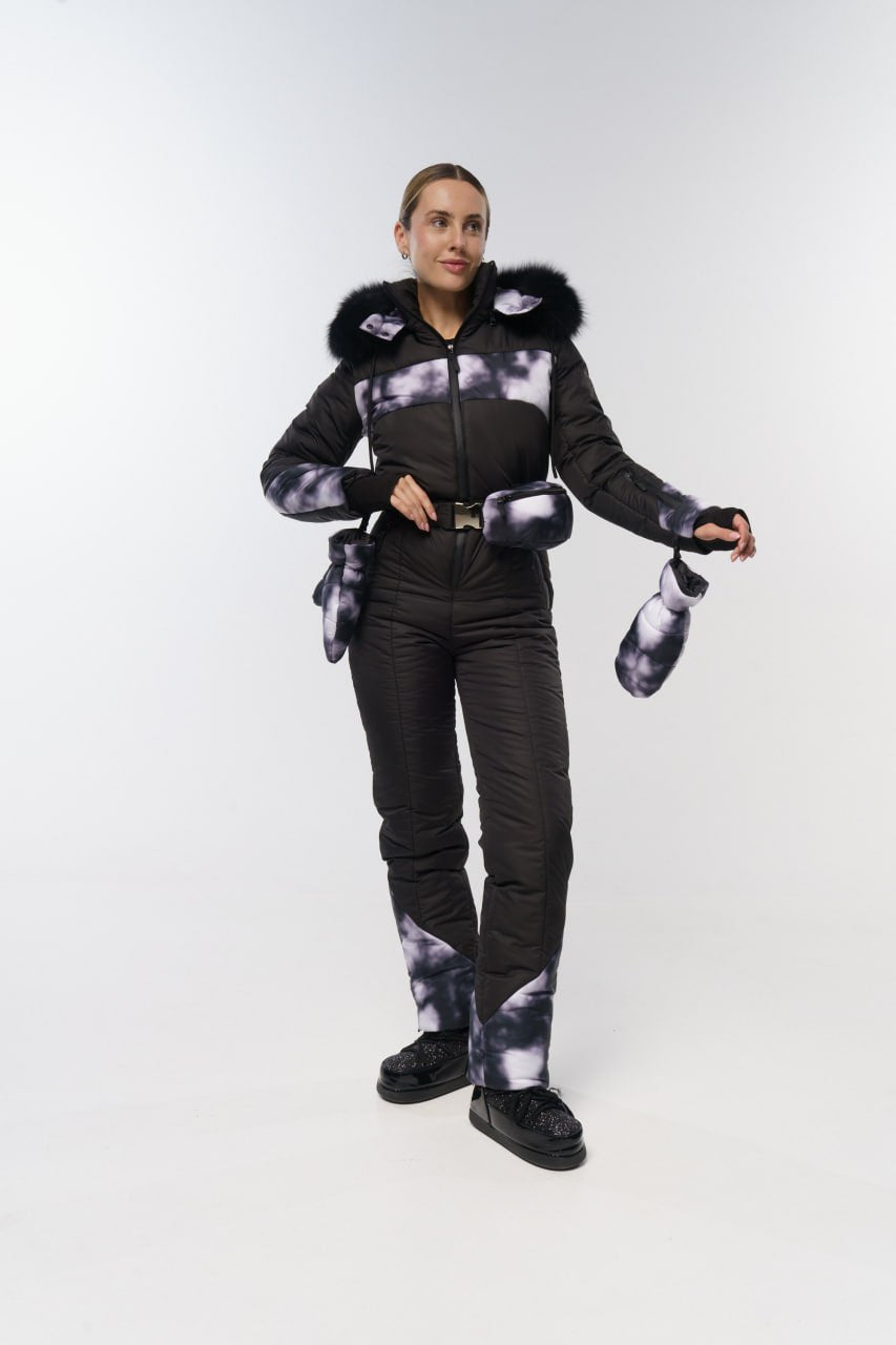 Person wearing a black and gray patterned snowsuit with fur-lined hood on a white background