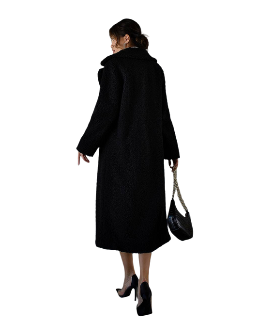 Woman wearing a black coat holding a black handbag on a white background